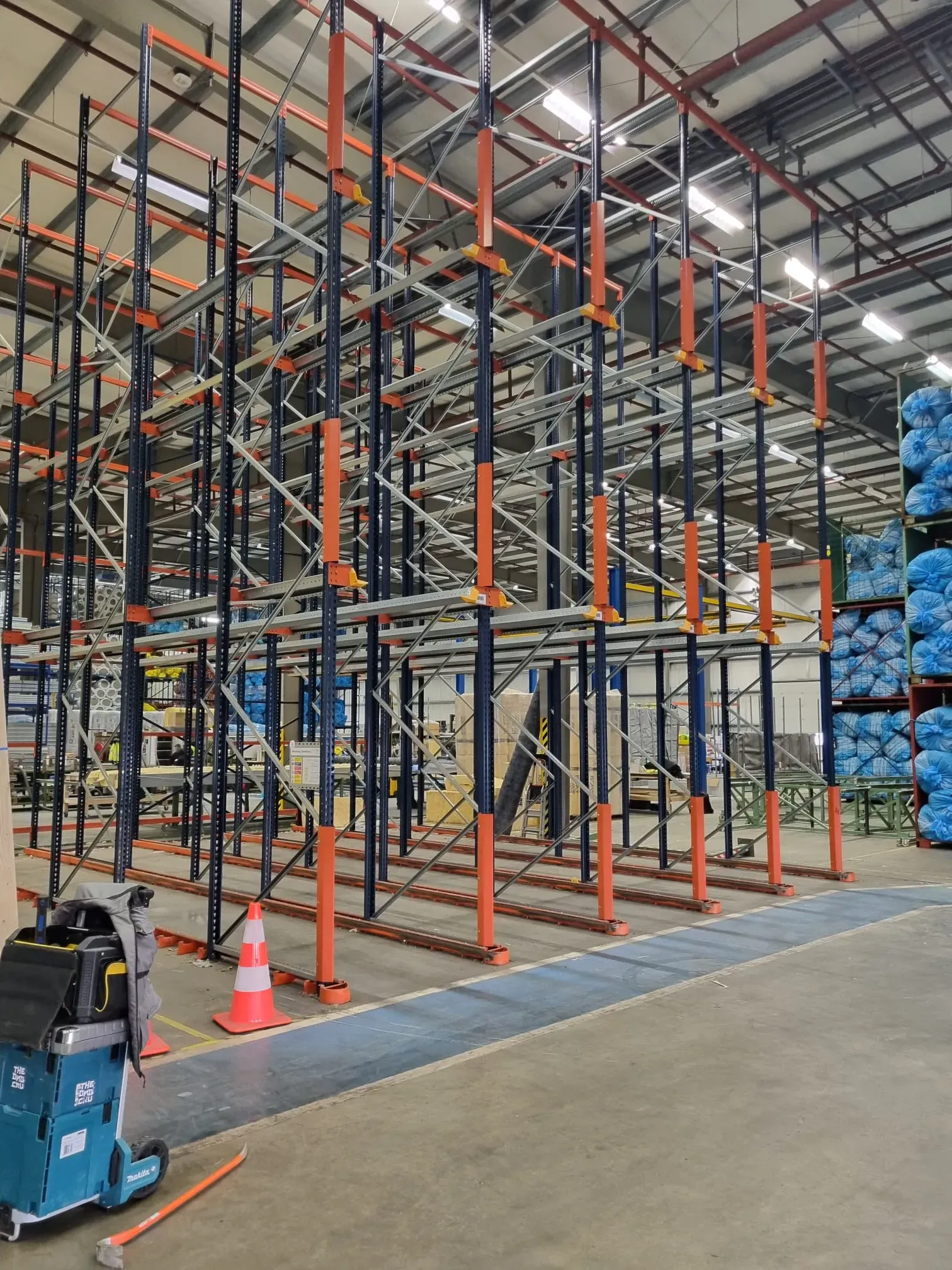 Magazijnstellingen in aanbouw met oranje en blauwe elementen in een ruime hal